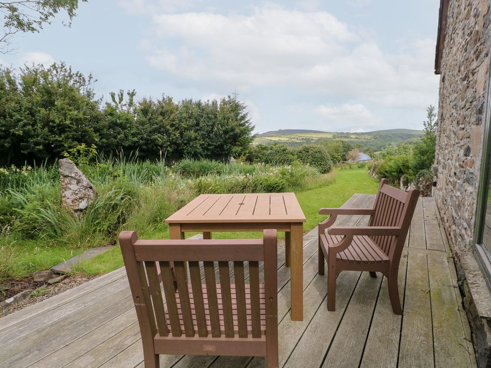 A table and chairs on a wooden deck overlooking greenery at The Dovecote near Fishguard