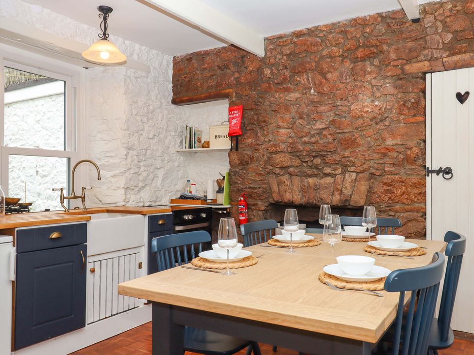 A kitchen with a dining table and chairs at Captains Cottage in Brixham