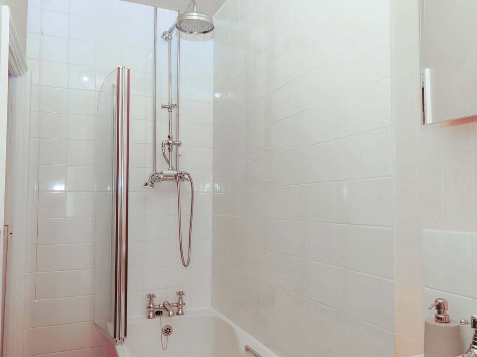 A bathroom with a bathtub and shower fixture at Captains Cottage in Brixham