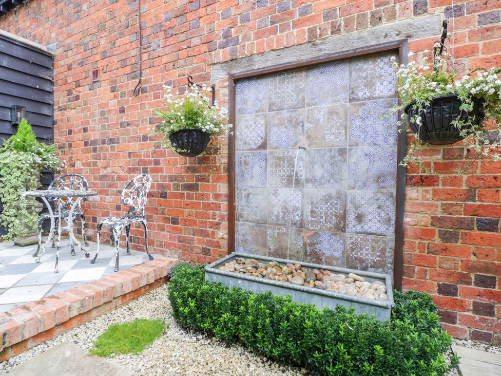 A garden with a water feature and seating area at The Sty Shades Farm near Malmesbury