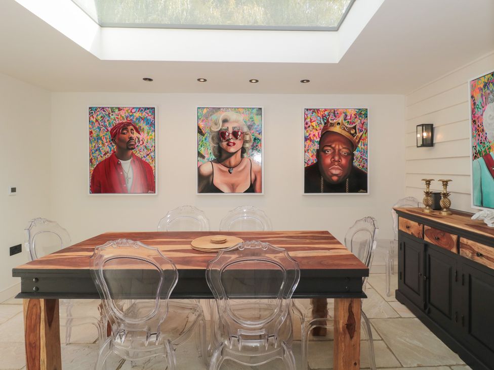A dining room with a wooden table and transparent chairs at The Sty Shades Farm near Malmesbury