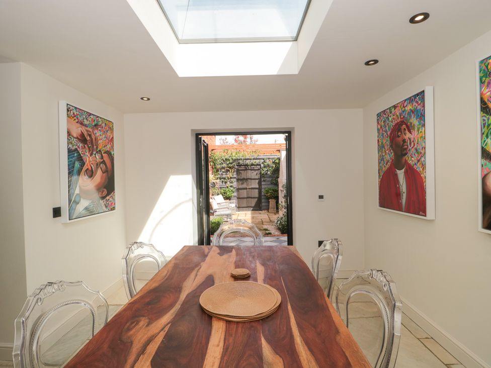 A dining room with a wooden table and artwork at The Sty near Shades Farm Malmesbury