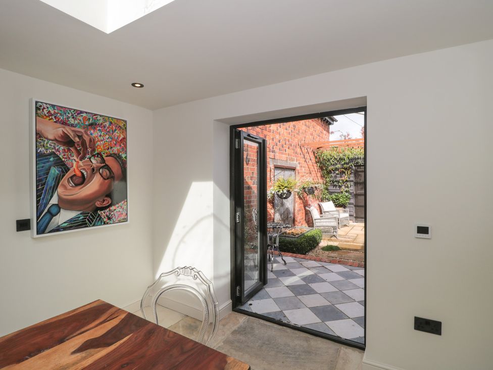 A dining room with a painting, table and door leading to outdoor area at The Sty, Shades Farm near Malmesbury