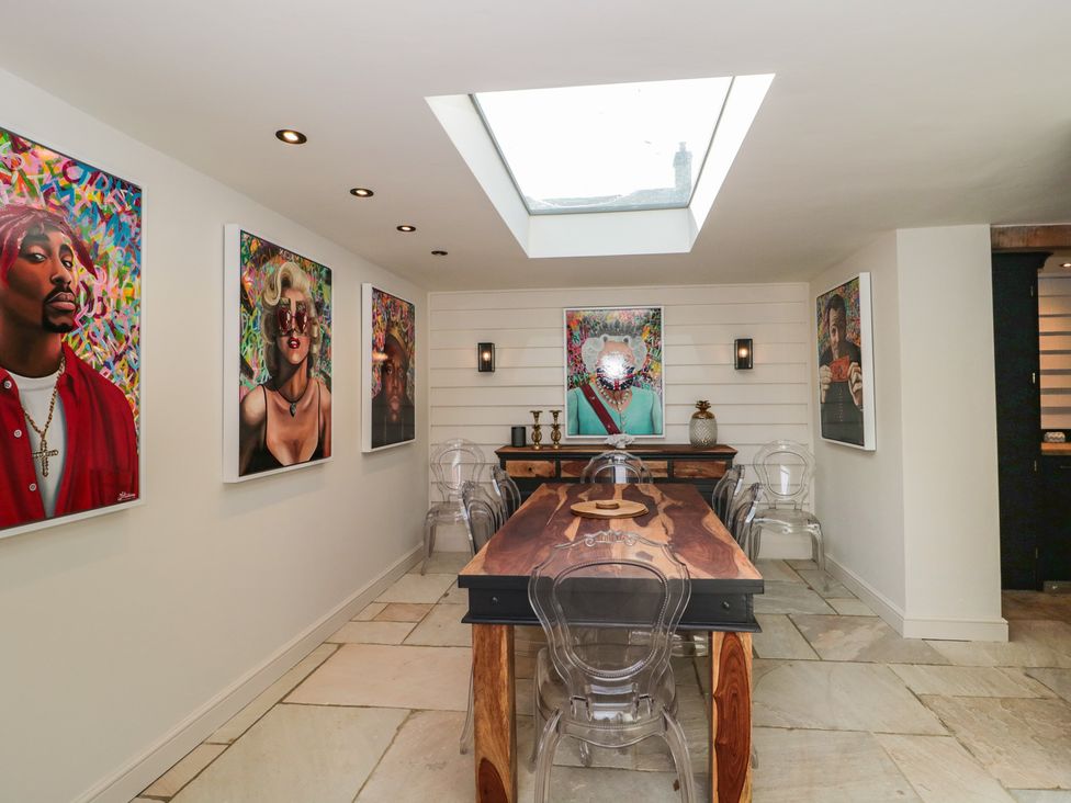 A dining room with a wooden table and artwork on the walls at The Sty near Malmesbury