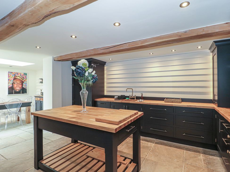 A kitchen with a wooden island and black cabinets at The Sty, Shades Farm near Malmesbury