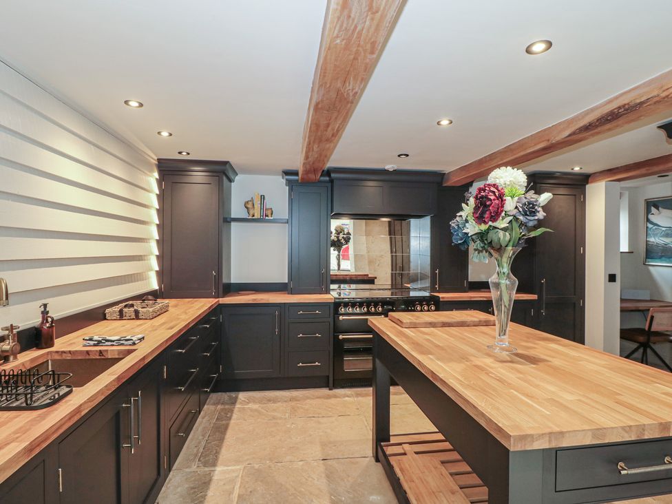 A kitchen with dark cabinets and a wooden countertop at The Sty Shades Farm near Malmesbury