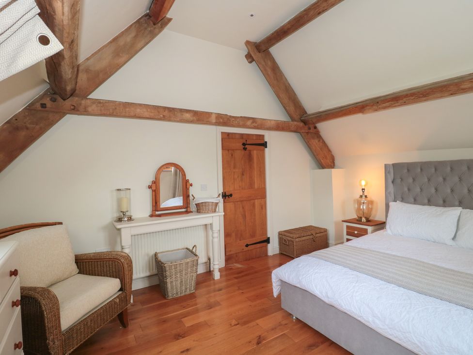 A bedroom with a bed, chair, and mirror at The Sty near Malmesbury