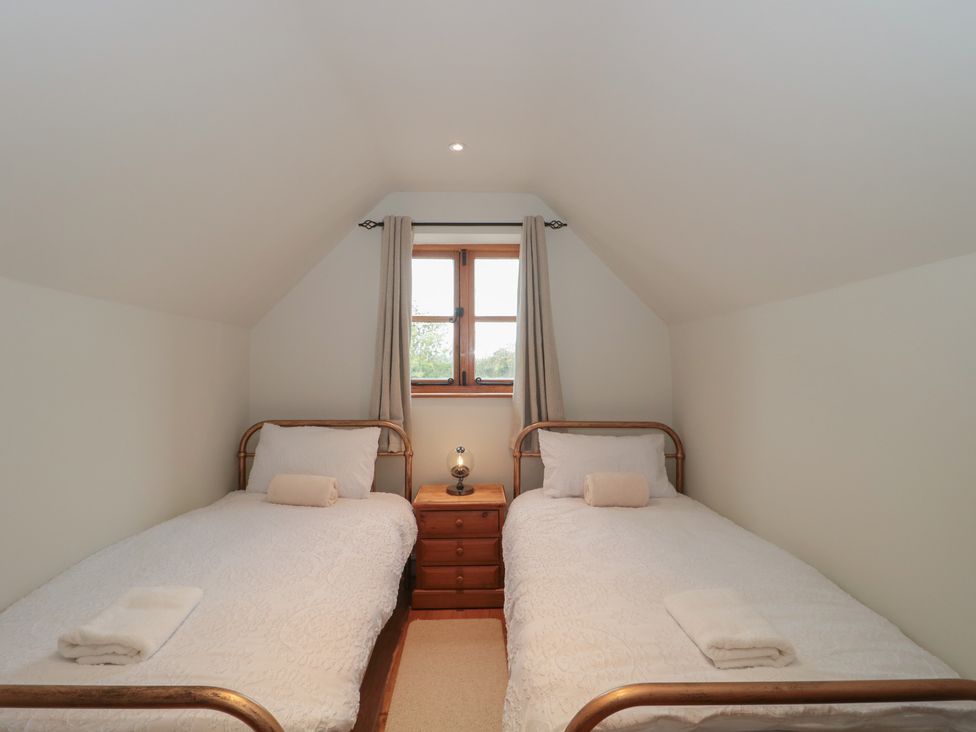 A bedroom with two single beds and a window at The Sty near Shades Farm Malmesbury