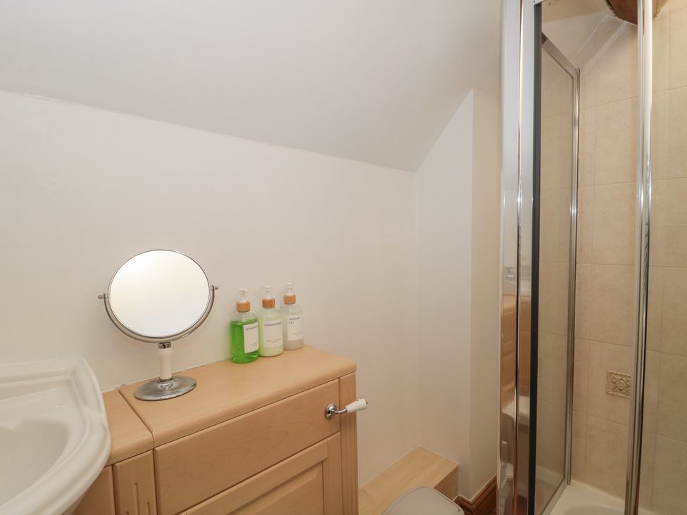 A bathroom with sink, mirror, shower, and toiletries at The Sty, Shades Farm near Malmesbury