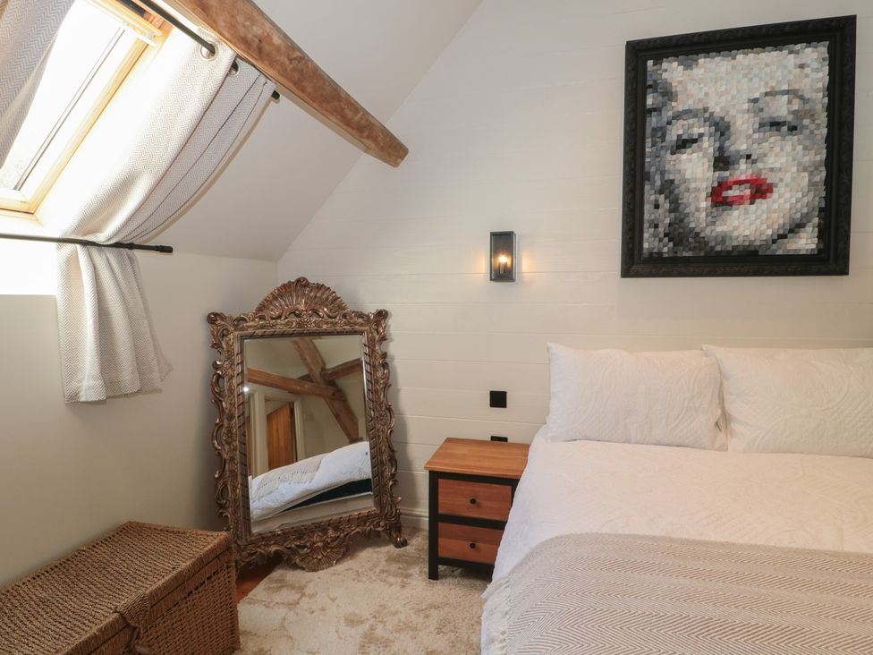 A bedroom with a bed, mirror, and painting at The Sty, Shades Farm near Malmesbury