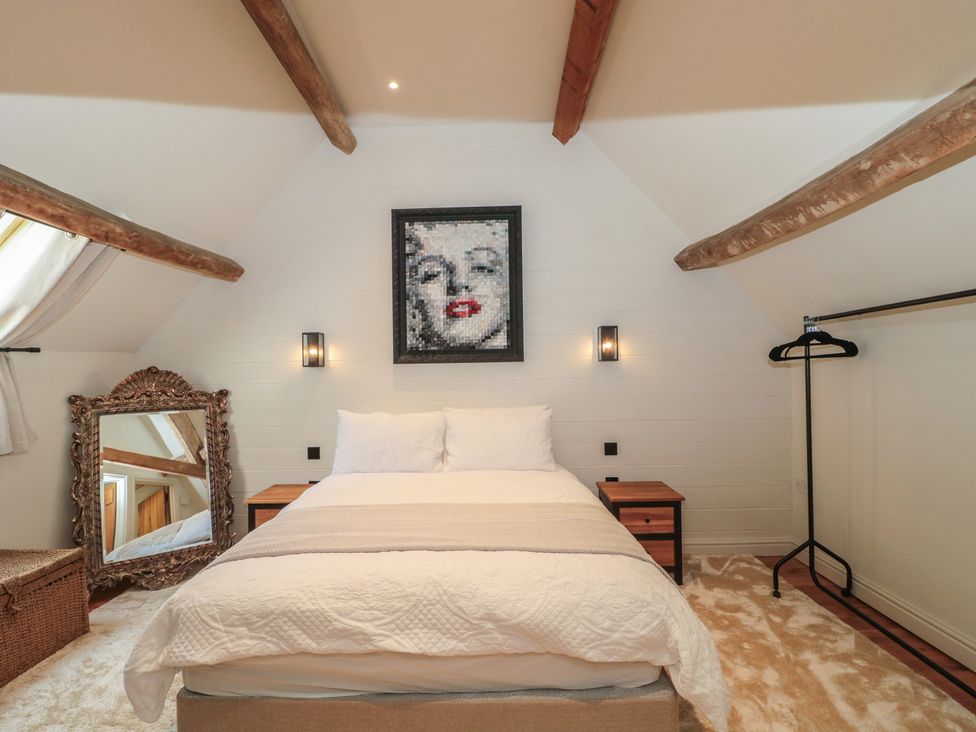 A bedroom with a bed and mirror at The Sty near Malmesbury