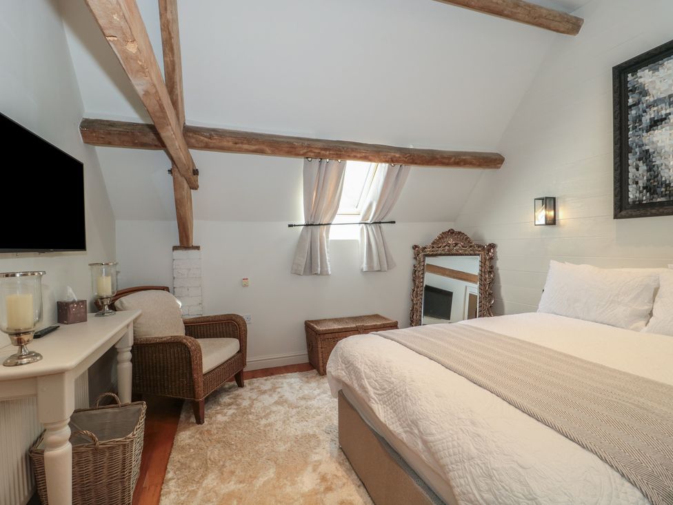 A bedroom with a bed, mirror, and chair at The Sty near Malmesbury