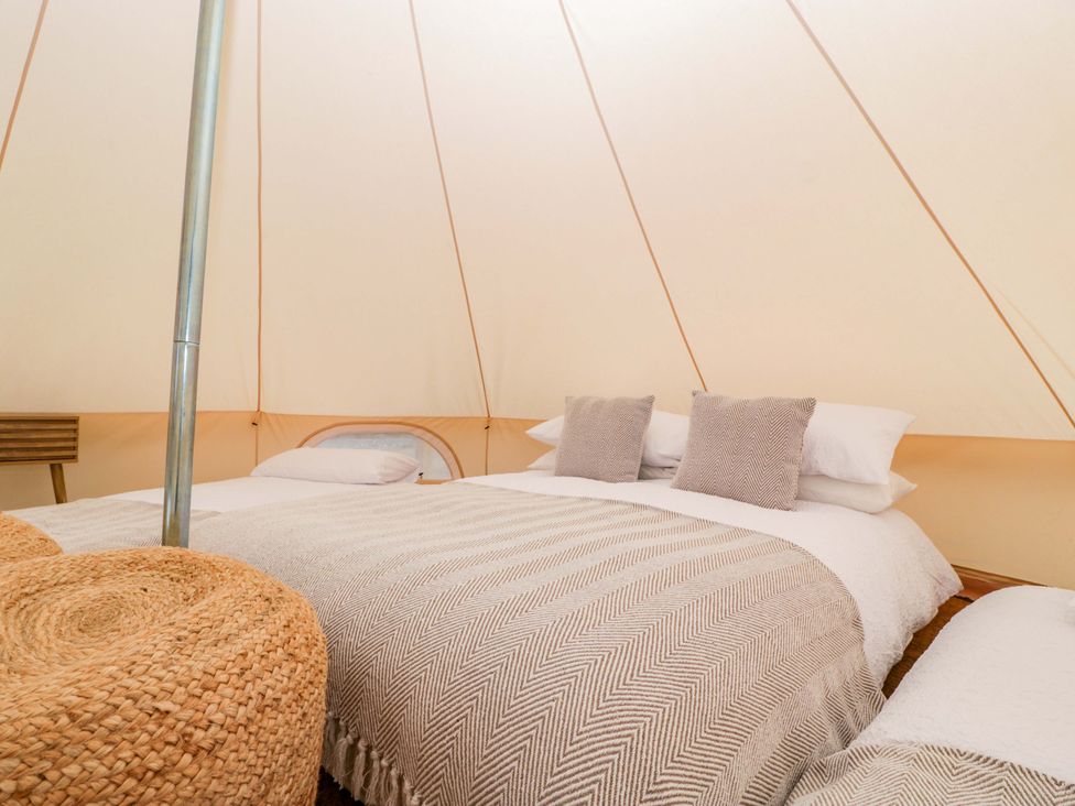 A bedroom with a bed and pillows in a tent at Bell 1 Shades Farm near Malmesbury