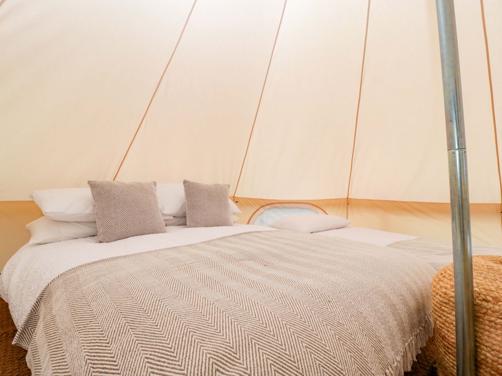 A bedroom with a bed and pillows in a tent at Bell 1 Shades Farm near Malmesbury
