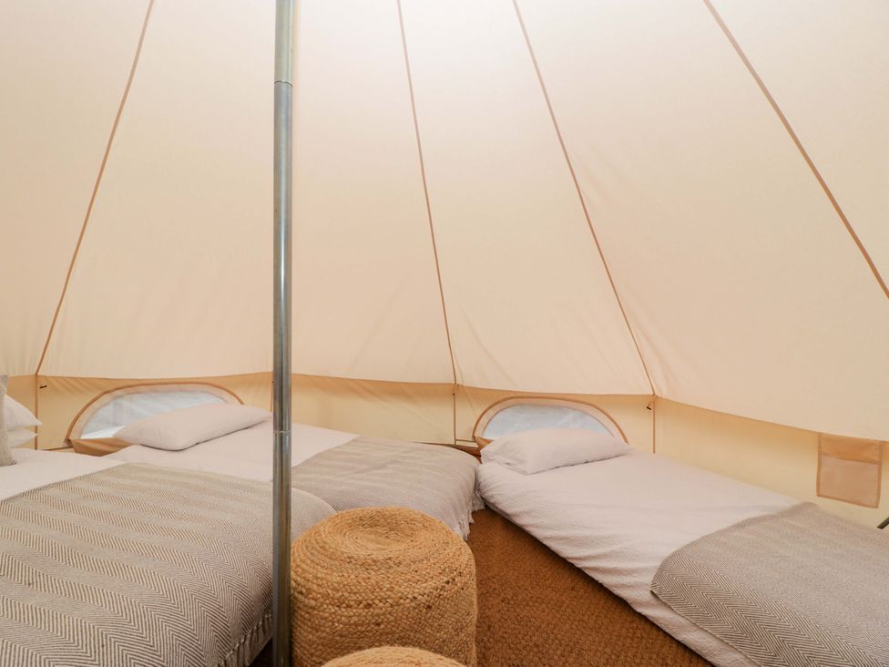 An interior of a glamping tent with two beds and a stool at Bell 1 near Shades Farm