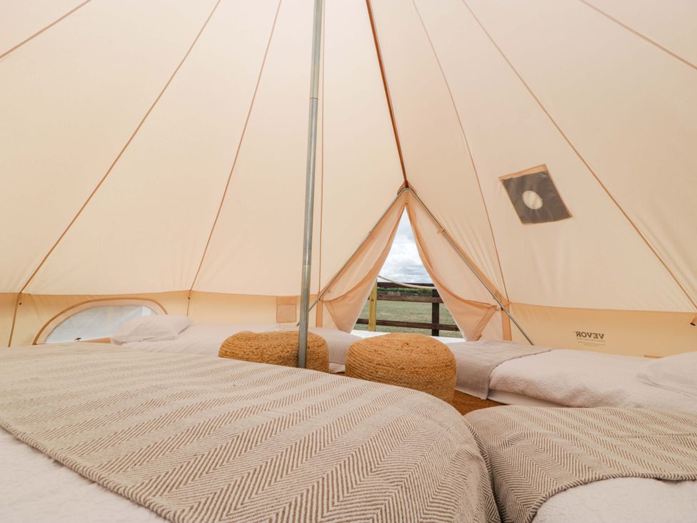 A bell tent with bedding and a view at Bell 1, Shades Farm near Malmesbury