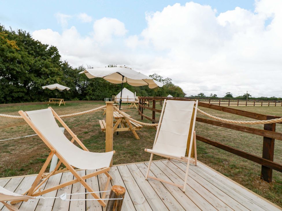 An outdoor area with sun loungers and a table at Bell 1 Shades Farm near Malmesbury