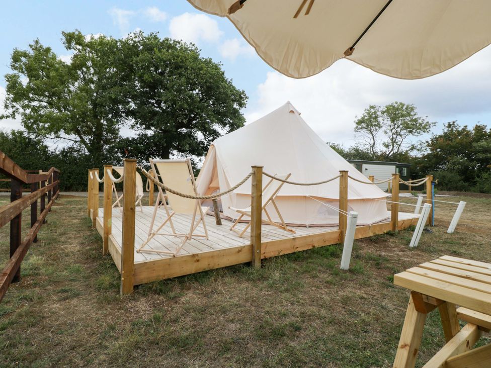 A glamping tent on a wooden deck with folding chairs at Bell 1 near Shades Farm near Malmesbury