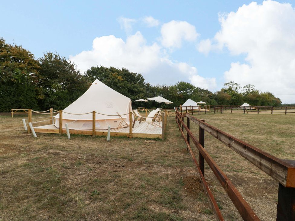 A glamping tent with sun loungers and wooden deck at Bell 1 near Shades Farm Malmesbury