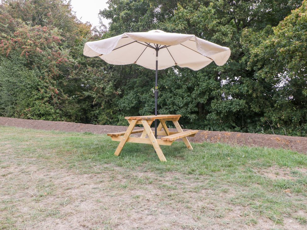 A picnic table with an umbrella in an outdoor area at Bell 1 Shades Farm near Malmesbury