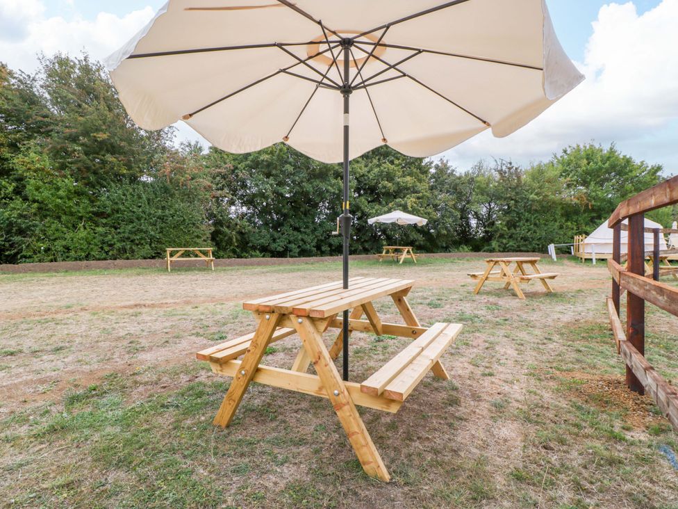 A table with an umbrella in an outdoor area at Bell 1 Shades Farm near Malmesbury