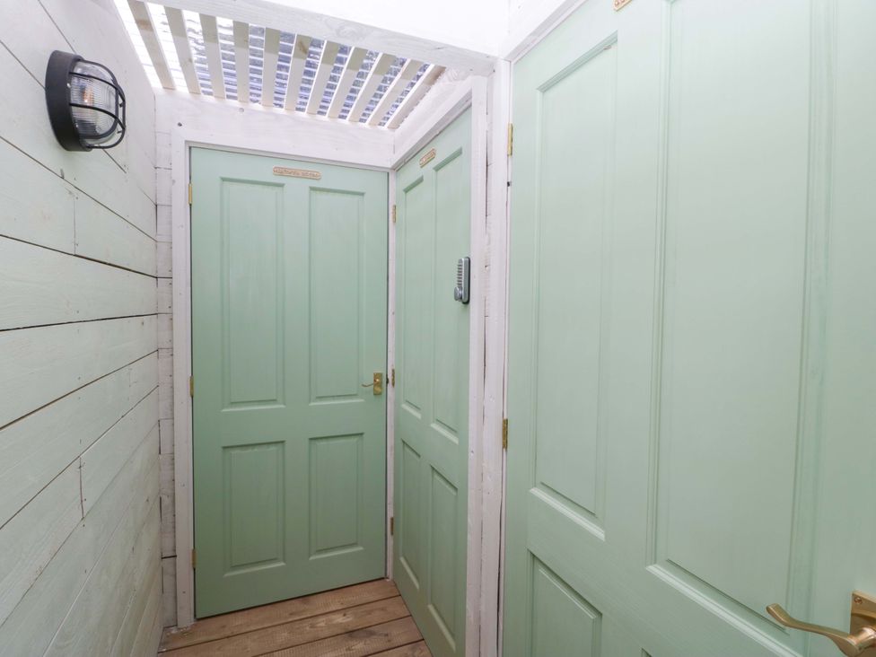 An entrance hallway with green doors and wooden panels at Bell 1 Shades Farm near Malmesbury