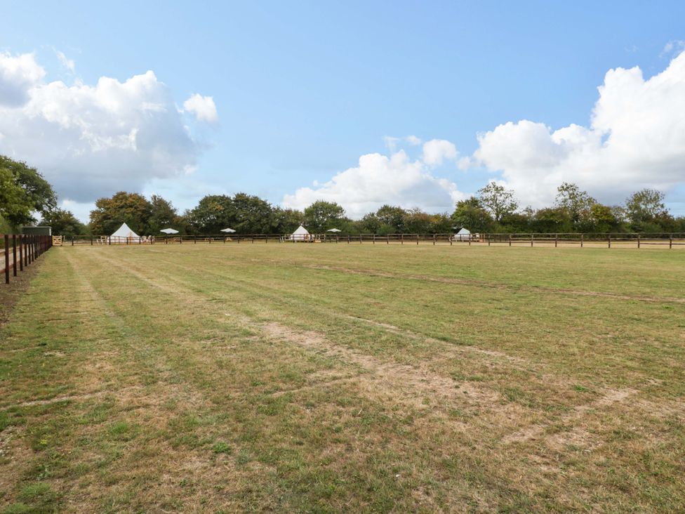 An open field with tents and trees at Bell 1 Shades Farm near Malmesbury