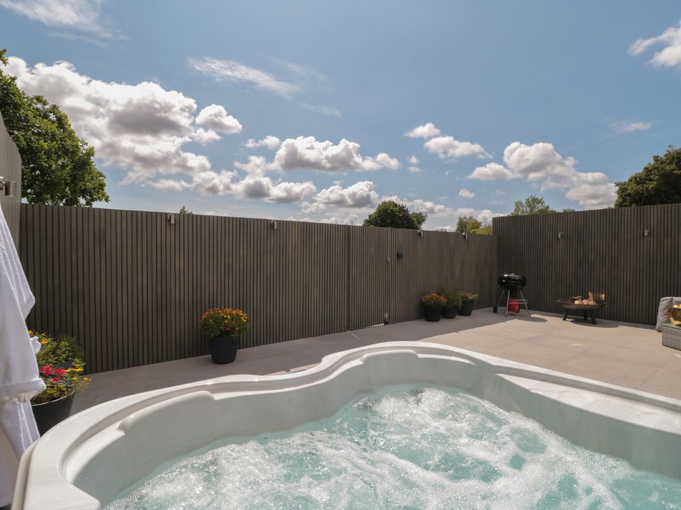 An outdoor area with a hot tub and patio furniture at Noflash Malpal in Bishop Sutton