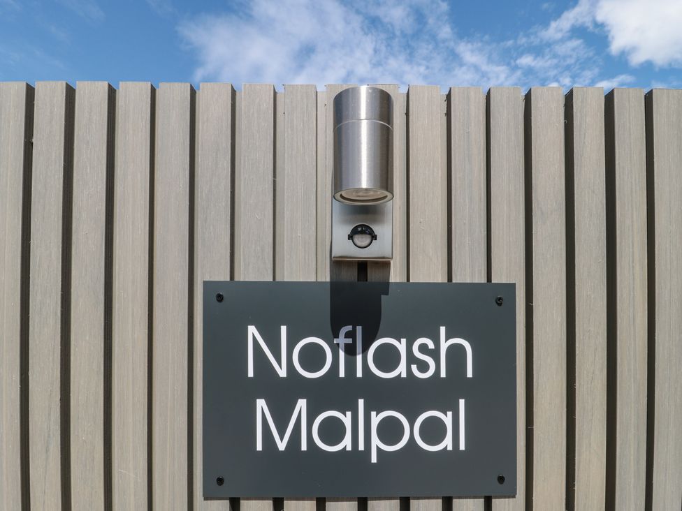 A sign with the name Noflash Malpal against a wooden wall in Bishop Sutton