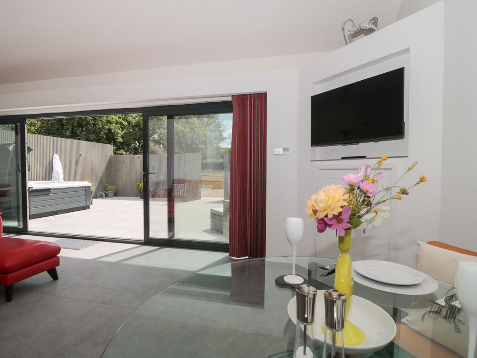 A living room with a glass table and red chair at Noflash Malpal in Bishop Sutton