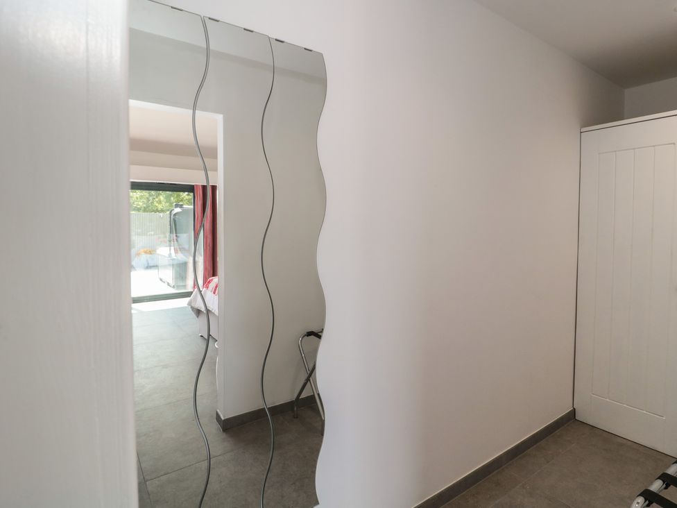 A hallway with a mirror and a view of a bedroom at Noflash Malpal in Bishop Sutton