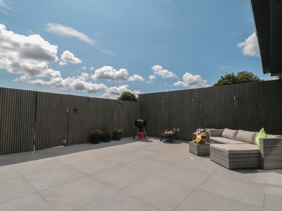 A patio with a sofa and barbecue grill at Noflash Malpal in Bishop Sutton