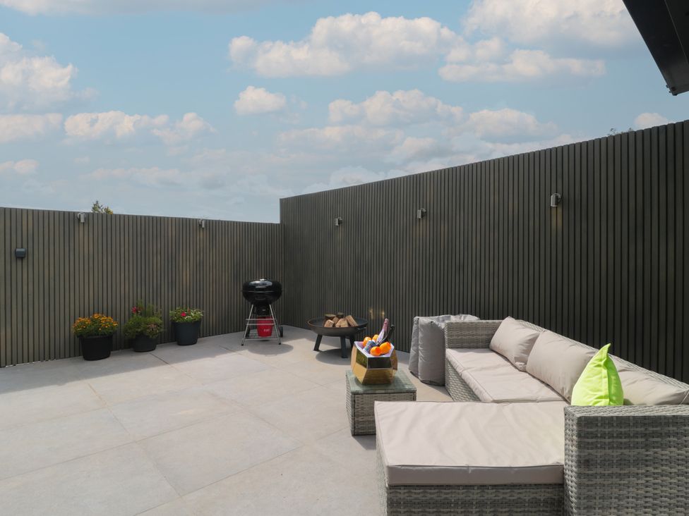 An outdoor terrace with a sofa and grill at Noflash Malpal in Bishop Sutton