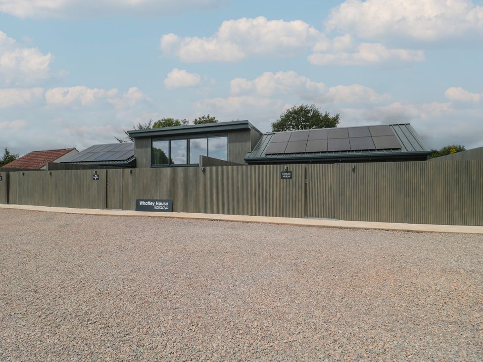 A house with solar panels and a fence at Whatley House Holidays in Bishop Sutton