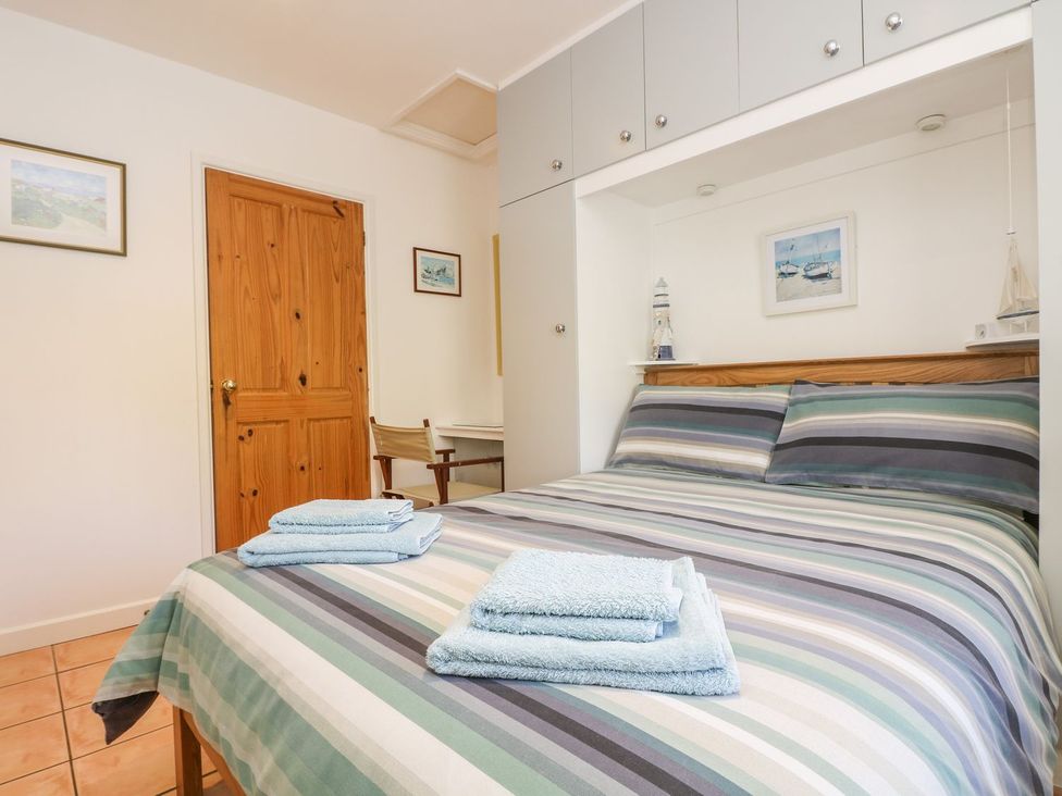 A bedroom with a bed and towels on a table at Tater-Du in Porthcurno