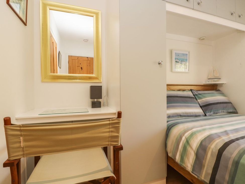 A bedroom with a bed and a mirror at Tater-Du in Porthcurno