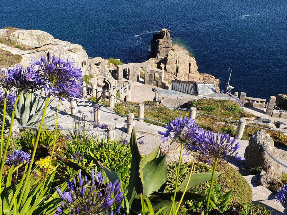 A rocky coastline with flowers and a pathway at Tater-Du in Porthcurno near Land’s End