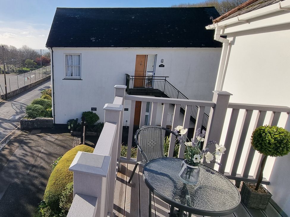 An outdoor balcony with a table and chairs at Tater-Du in Porthcurno near Land’s End
