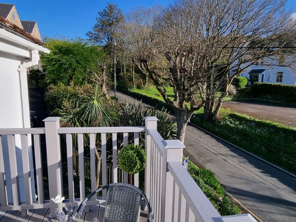 A balcony with a table and chair overlooking a road at Tater-Du Porthcurno near Land’s End