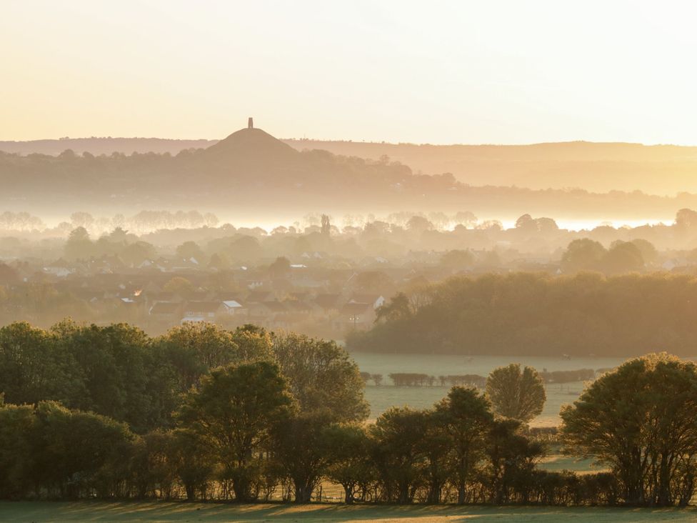 A view of a misty landscape with a hill and village at The Mill House in Glastonbury