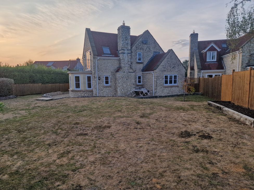 A garden with a house and patio area at The Mill House in Glastonbury