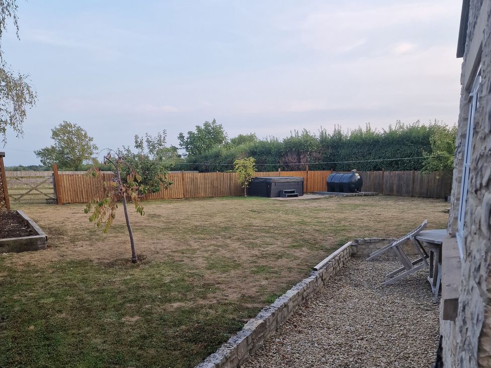 A garden with a hot tub and tree at The Mill House in Glastonbury