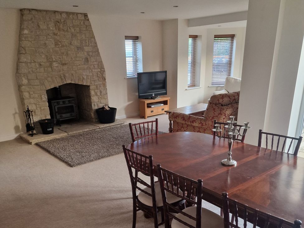 A living room with a fireplace and a dining table at The Mill House in Glastonbury