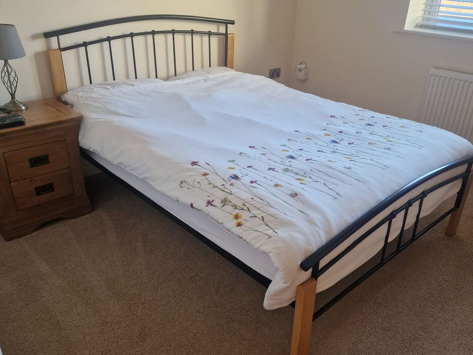 A bed with bedding and a bedside table at The Mill House in Glastonbury