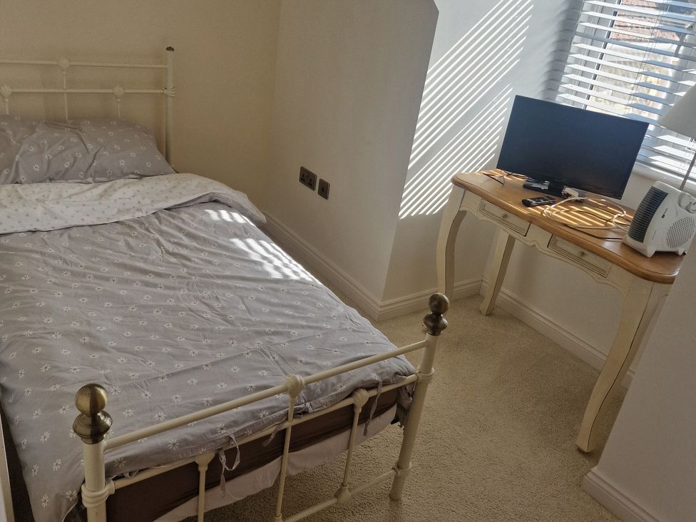 A bedroom with a bed and television on a table at The Mill House in Glastonbury