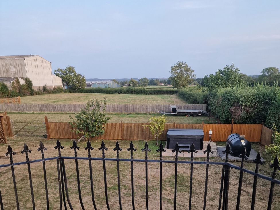 An outdoor space with a hot tub and fence at The Mill House in Glastonbury