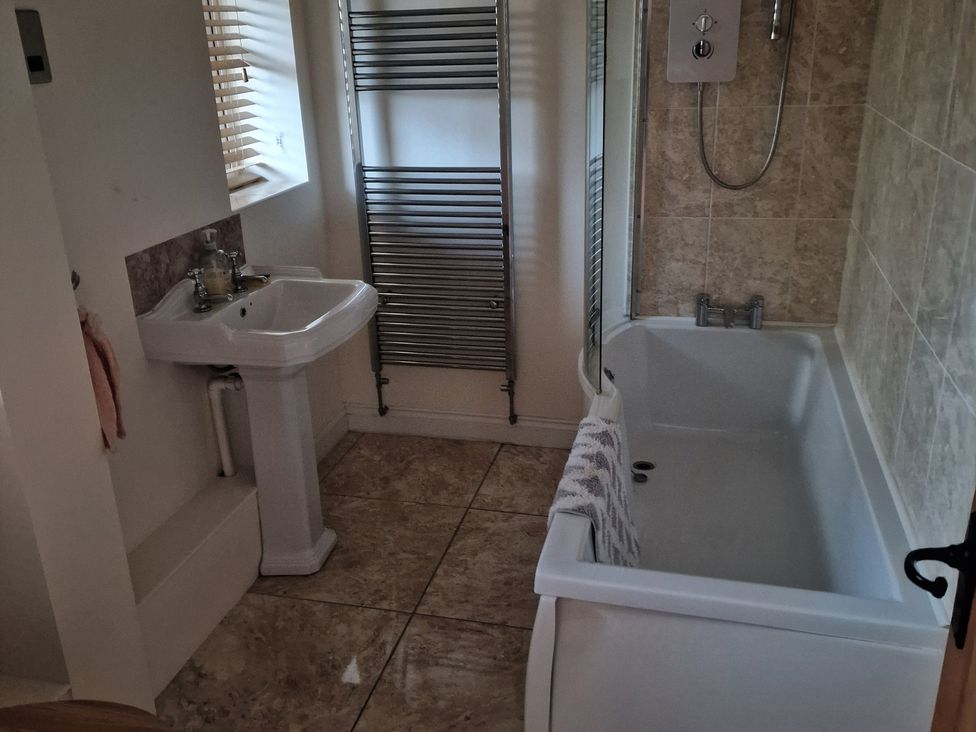 A bathroom with a bathtub, sink, and towel rack at The Mill House in Glastonbury