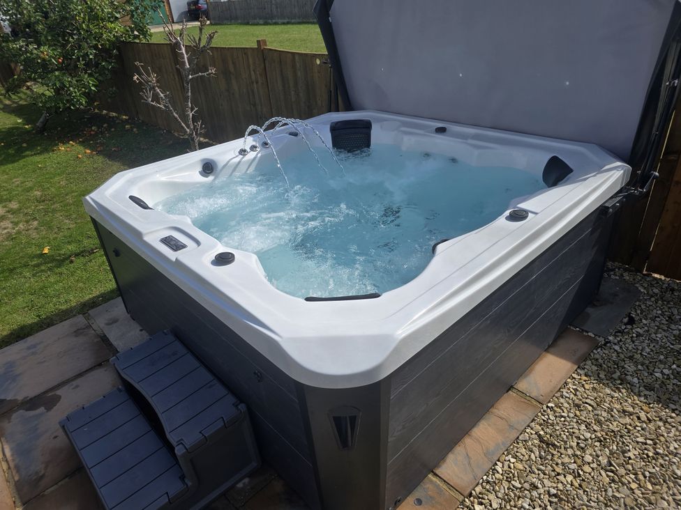 A hot tub with water in a garden area at The Mill House in Glastonbury