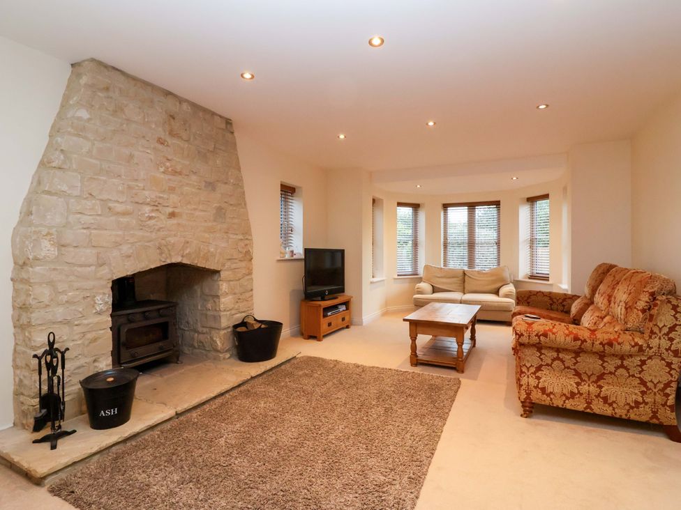 A living room with a stone fireplace and a television at The Mill House in Glastonbury