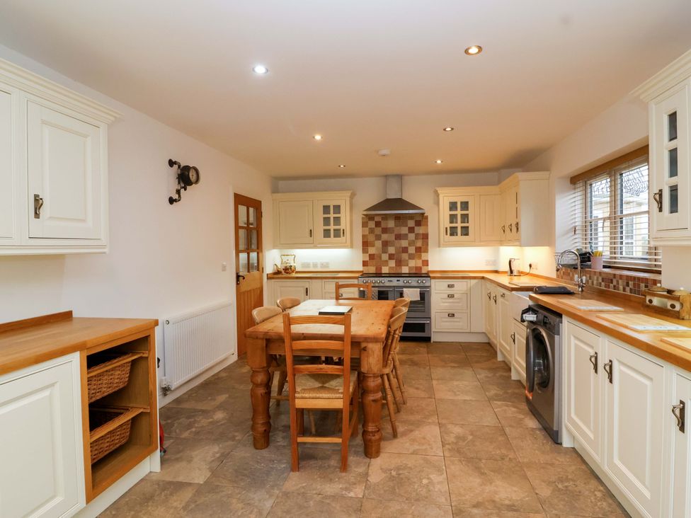 A kitchen with a dining table and wooden cabinets at The Mill House in Glastonbury